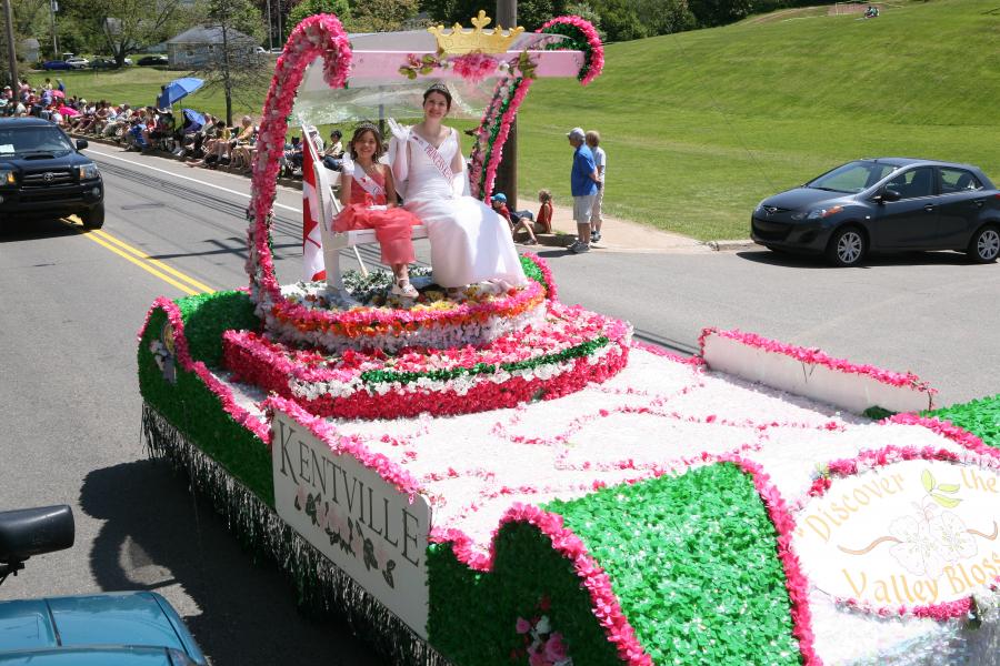 a float with princess kentville up top rides by in the apple blossom parade