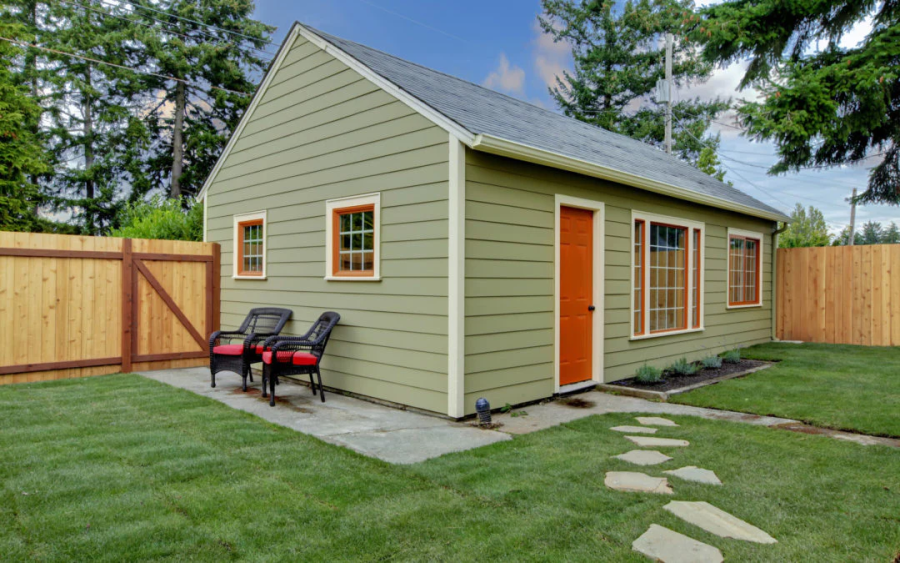 a garage suite with green siding and a red door
