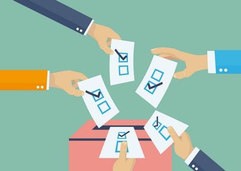 hands voting in a ballot box